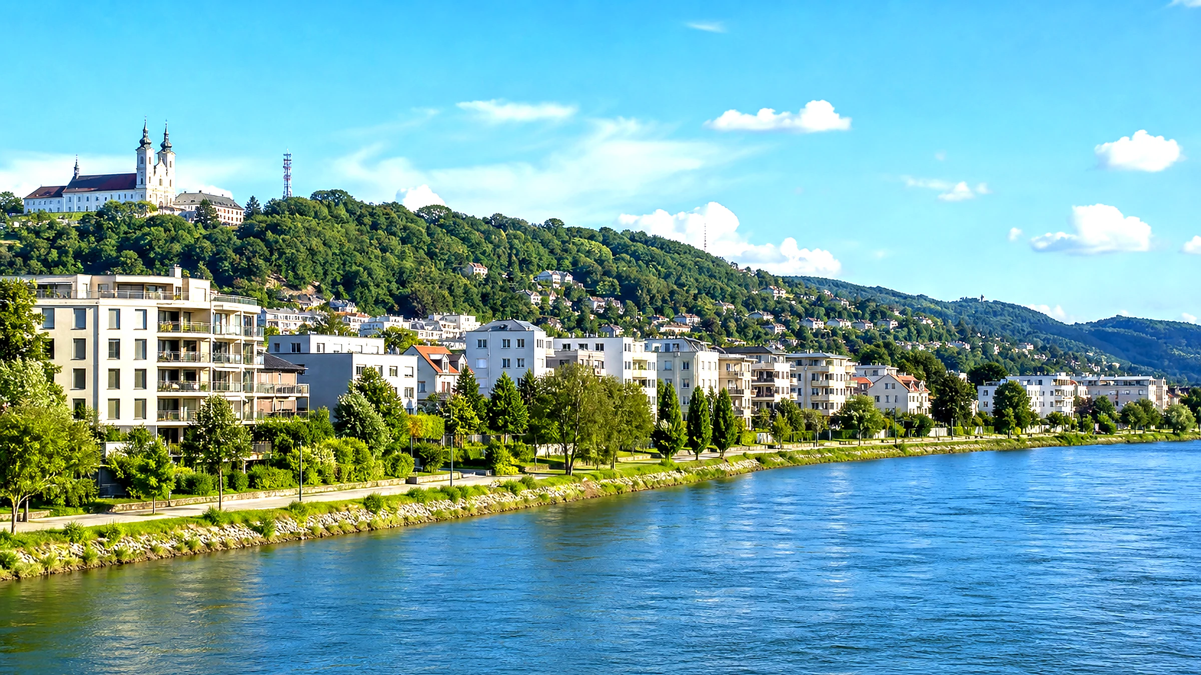 Wohnhäuser an einem Fluss mit bewaldeten Hängen
